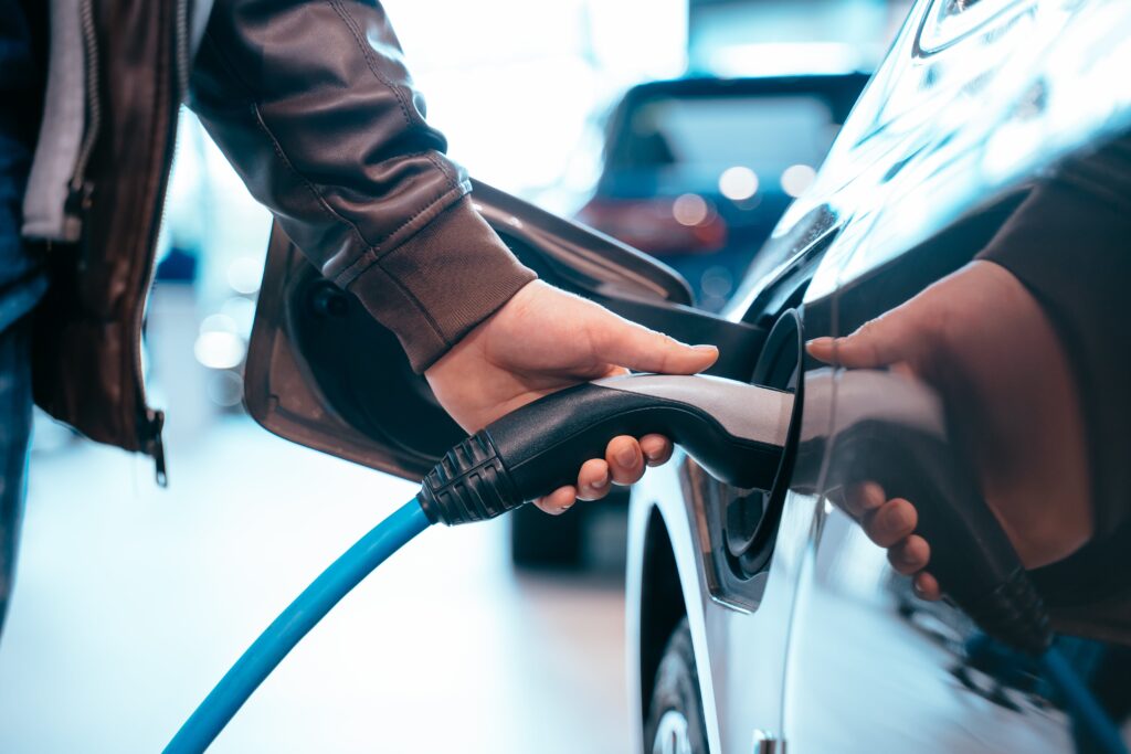 human-hand-is-holding-electric-car-charging-connect-to-electric-car-min